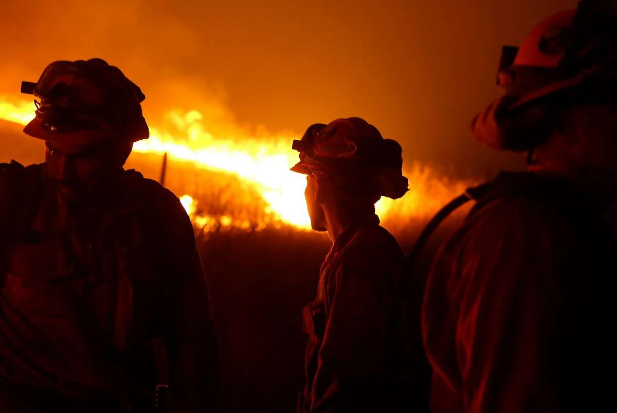 California Department of Corrections and Rehabilitation inmates stand guard as flames from the Butte Fire approach a containment line Saturday, Sept. 12, 2015 near San Andreas, Calif.(AP Photo/Rich Pedroncelli)