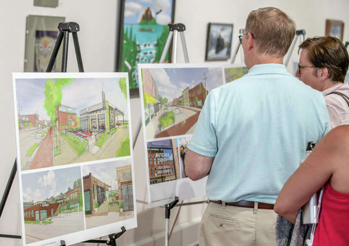 Guests study mock-up images Tuesday of plans John and Jayne Simmons has for the future of downtown Alton.