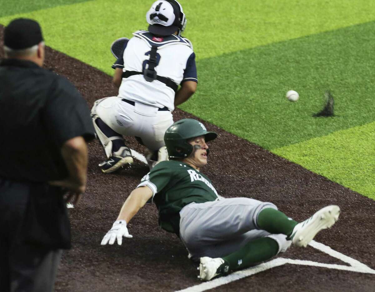Reagan's Zane Raba slides home for a score against O'Connor catcher Javier Perez in Game 2 of their best-of-3 first-round baseball playoff series at North East Sports Park on Friday, May 3, 2019. Reagan defeated O'Connor, 10-4, to move on to the next round of the playoffs. (Kin Man Hui/San Antonio Express-News)