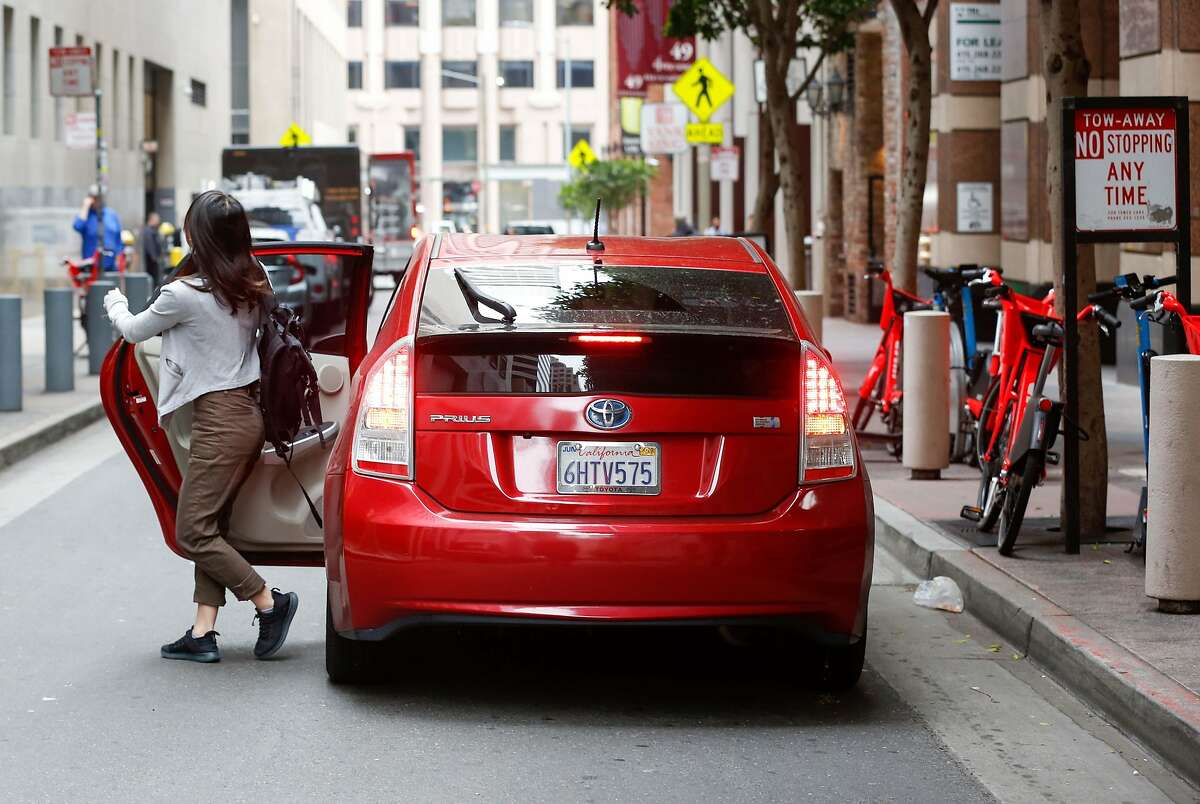 A woman exits a double parked rideshare car downtown on Stevenson Street on Wednesday, May 8, 2019 in San Francisco, Calif.