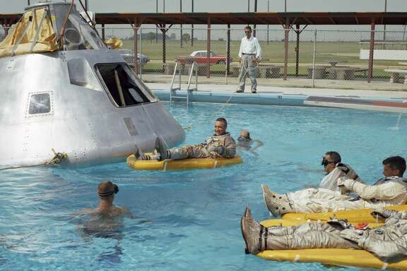 In this June 1966 photo, the prime crew for the first manned Apollo mission practice water egress procedures with full scale boilerplate model of their spacecraft. In the water at right is astronaut Edward H. White (foreground) and astronaut Roger B. Chaffee. In raft near the spacecraft is astronaut Virgil I. Grissom. NASA swimmers are in the water to assist in the practice session that took place at Ellington AFB, near the Manned Spacecraft Center, Houston.