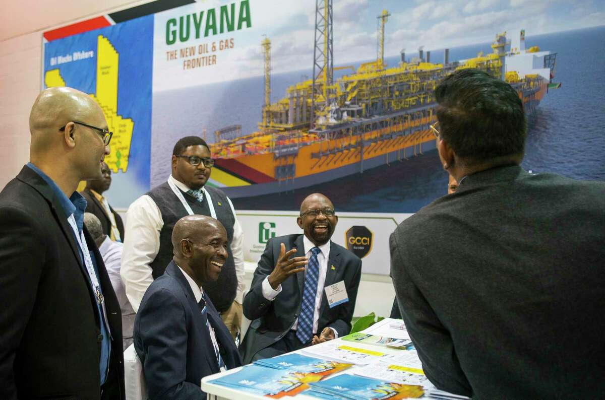 Alex Graham, center, CEO of Tagman Media Inc, laughs while a group talks at the Guyana booth during the annual Offshore Technology Conference inside NRG Arena, Tuesday, May 7, 2019. The conference, which usually takes place every May at NRG Center but was canceled this year, has booked its 2021 conference, though a little later than is typical. The event is scheduled to take place Aug. 16-19, 2021, “due to the ongoing challenges presented by COVID-19,” organizers said last month.