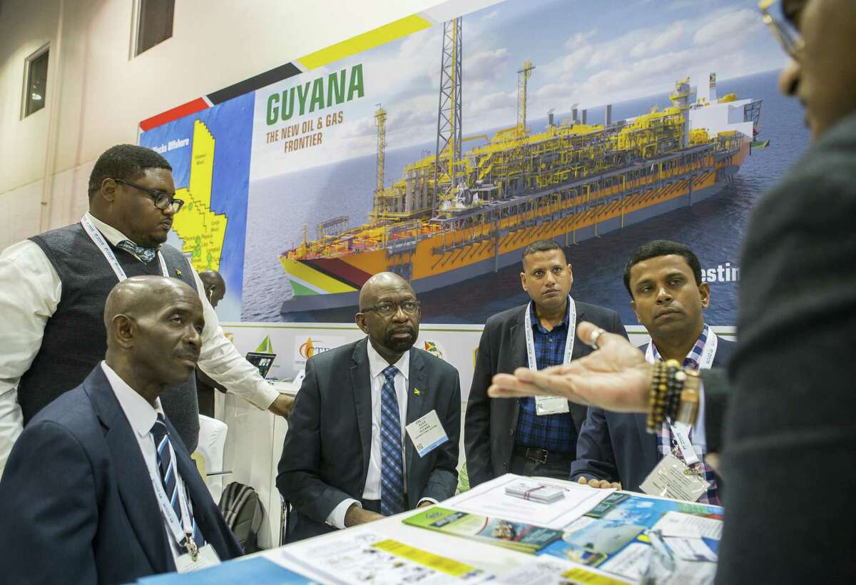 Alex Graham, center, CEO of Tagman Media Inc, listens while a group talks at the Guyana booth during the annual Offshore Technology Conference inside NRG Arena, Tuesday, May 7, 2019. Guyana has a presence at the conference for the first time this year.
