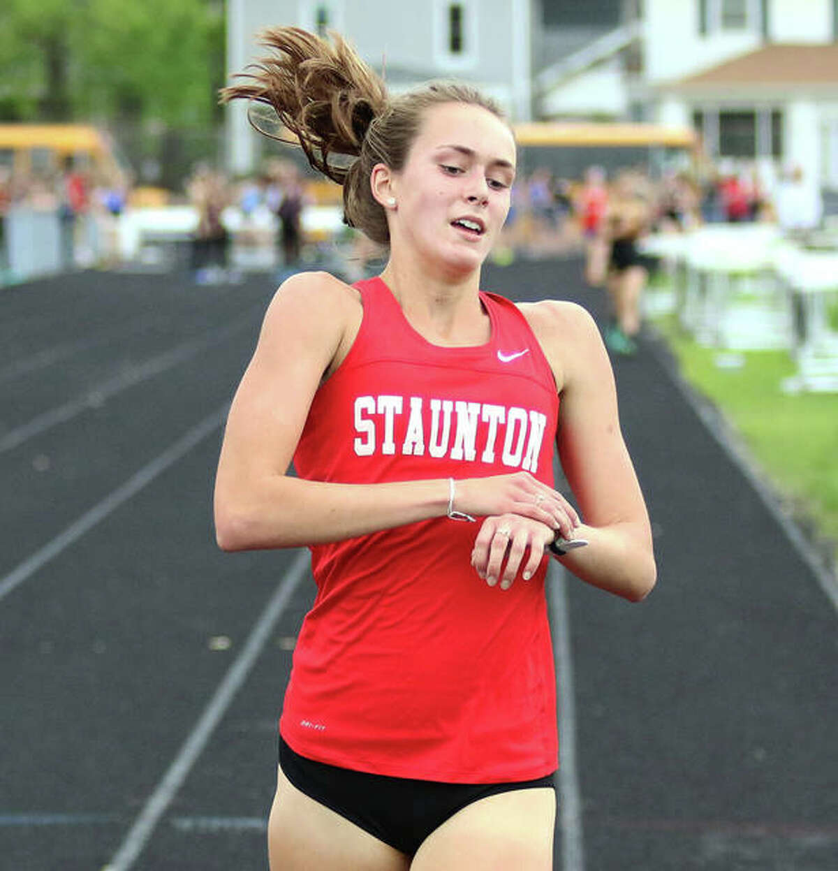 Staunton’s Lydia Roller stops her watch after finishing more than a lap ahead of the field in the 3,200 meters Monday at the Springfield Lanphier Class 2A Sectional.