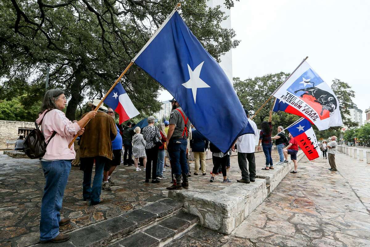 Keri Hillyer (left) with This is Texas Freedom Force, holds a flag with others in front of the Alamo as State Rep. Kyle Biedermann, R-Fredericksburg, holds a news conference at the Cenotaph to speak against the current Alamo master plan and to urge officials to include Texas Legislature in the negotiations going forward on Friday, Sept. 14, 2018.