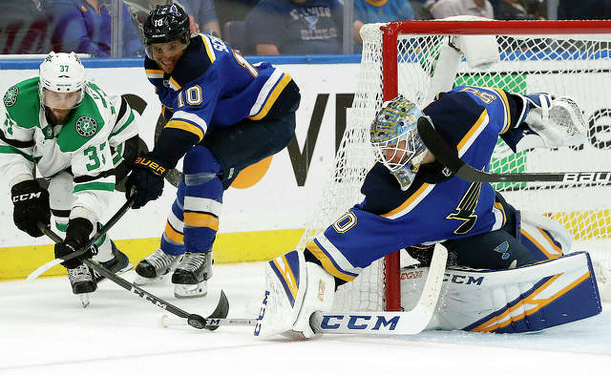Blues goalie Jordan Binnnington slaps the puck away from the Stars’ Justin Dowling (37) as Blues defender Brayden Schenn watches in Game 7 of their Western Conference semifinal series Tuesday in St. Louis.