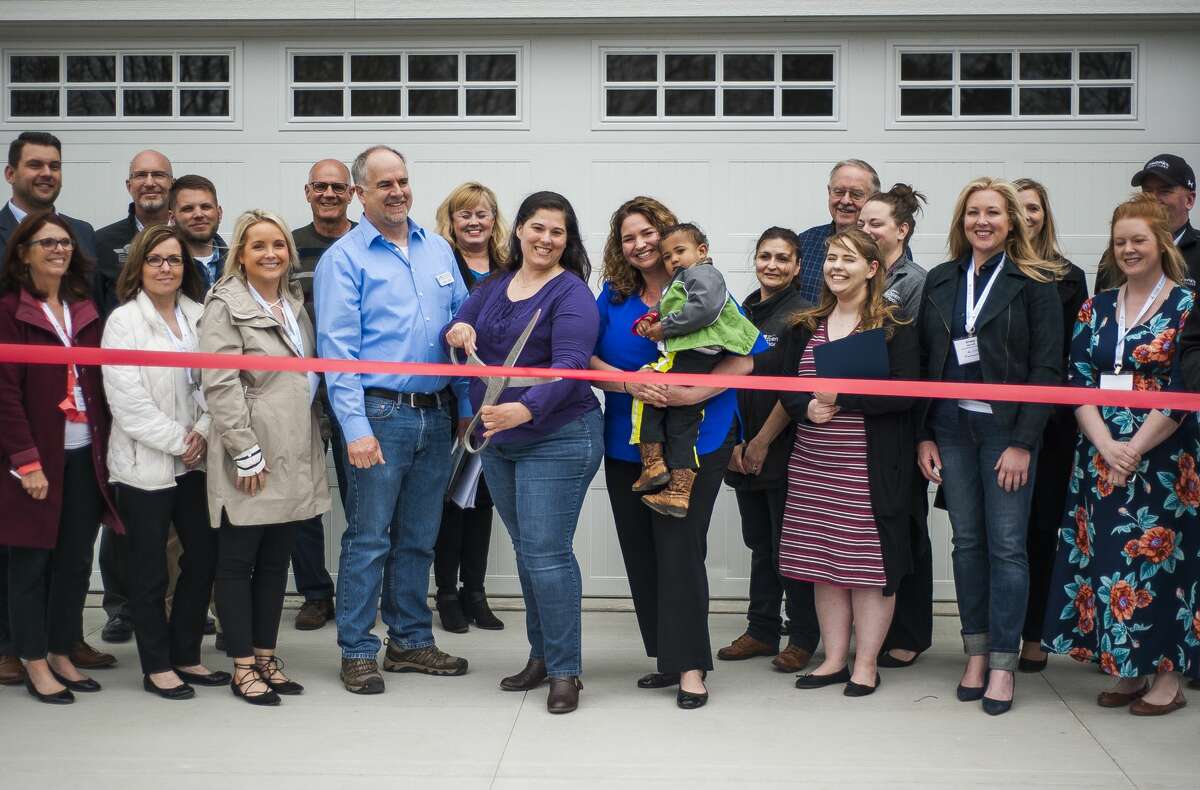 Midland's Open Door Executive Director Renee Pettinger, center right, poses for a photo with project partners before cutting a ribbon to commemorate the completed construction of a custom built home by Greystone Homes, the proceeds of which will benefit Midland's Open Door programs assist homeless mothers, on Wednesday, May 8, 2019 at 3060 Alderberry Court in Midland. (Katy Kildee/kkildee@mdn.net)