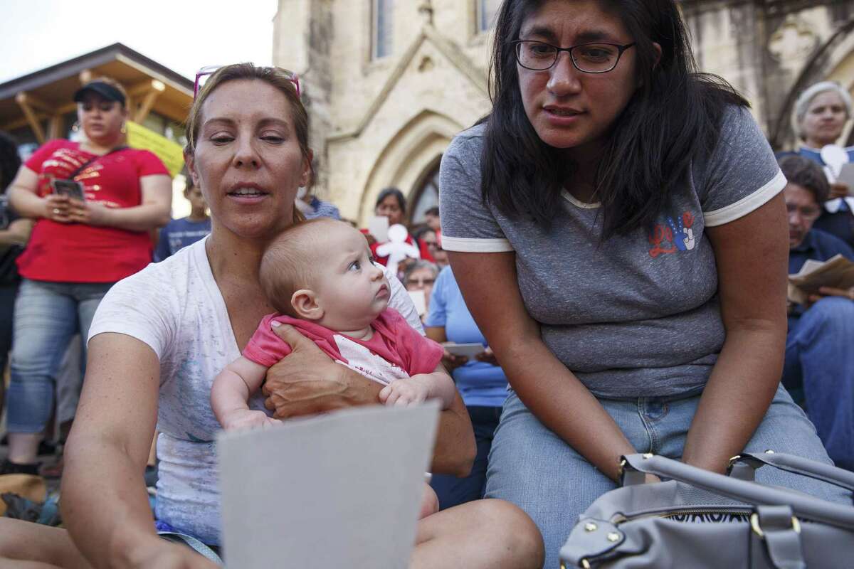 San Antonio District 5 Councilwoman, Shirley Gonzales, with her daughter Celina, reads a group prayer with Jacqueline Bedson, right, at the Vigil for Humanity, organized by a coalition of faith and justice organizations, on the main plaza in front of the San Fernando Cathedral where hundreds were in attendance on June 24, 2018. Gonzales said that San Antonio is a family based city so the "issue is very dear to me. I'm also a product of immigrants. [Separation of families] is against our core values as a city. We believe we have to fight injustice."