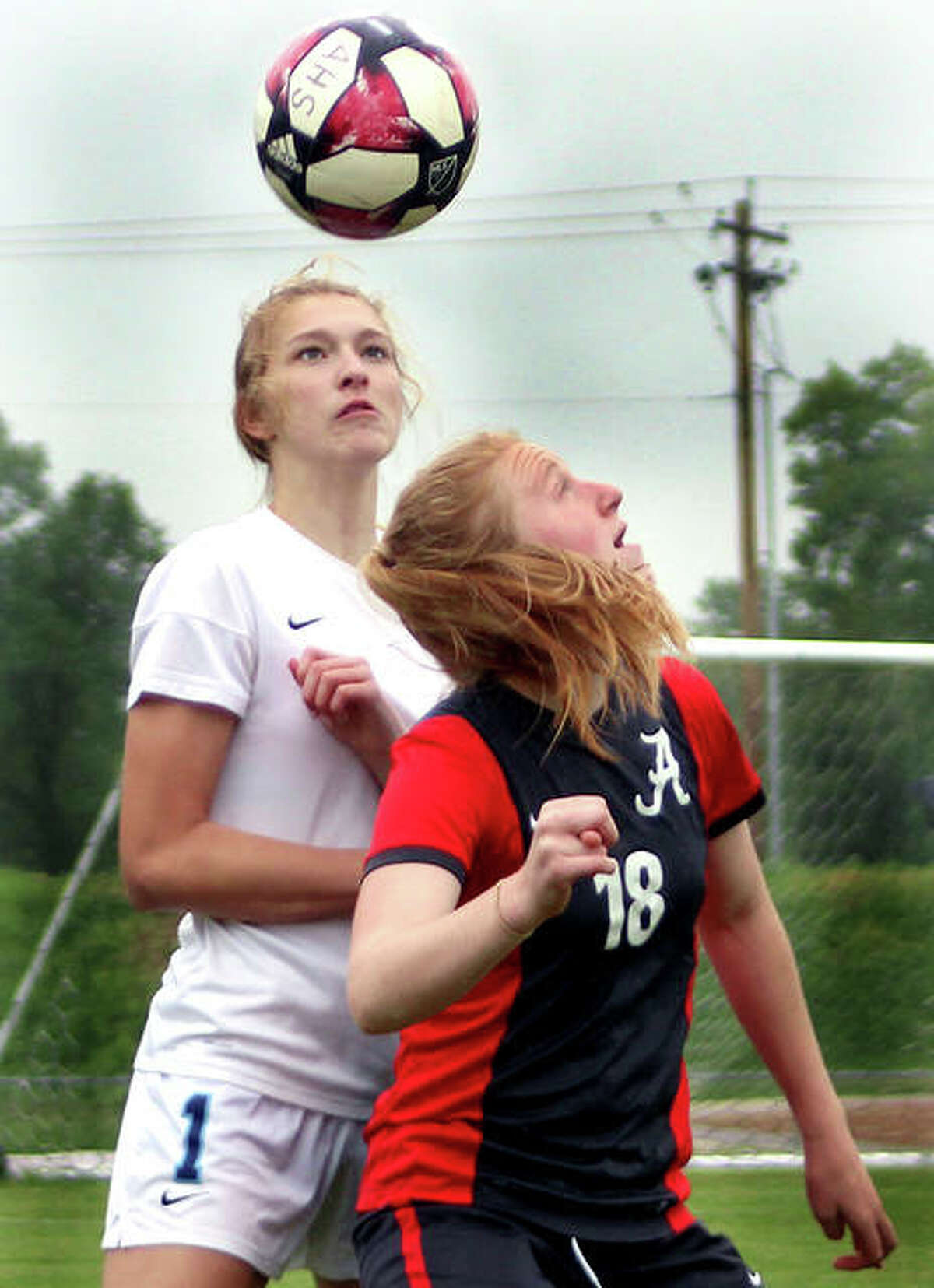 Maggie Evans of Alton (18) eyes the ball after heading it in front of Belleville East’s Abigail Kuykendall Thursday night at Alton High. The Redbirds got past East 2-1 in overtime penalty kicks.