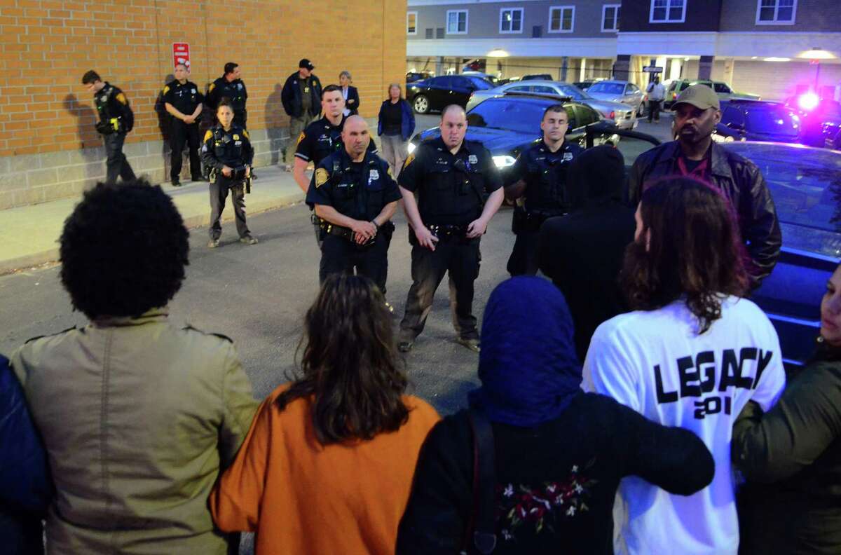 Activists and friends of Jayson Negron link arms as they confront Bridgeport police officers in the parking lot of the Walgreen's along Fairfield Ave in Bridgeport, Conn., on Thursday May 9, 2019. They were there to mark the second anniversary of Negron's death after he was shot and killed by a police officer near the pharmacy.