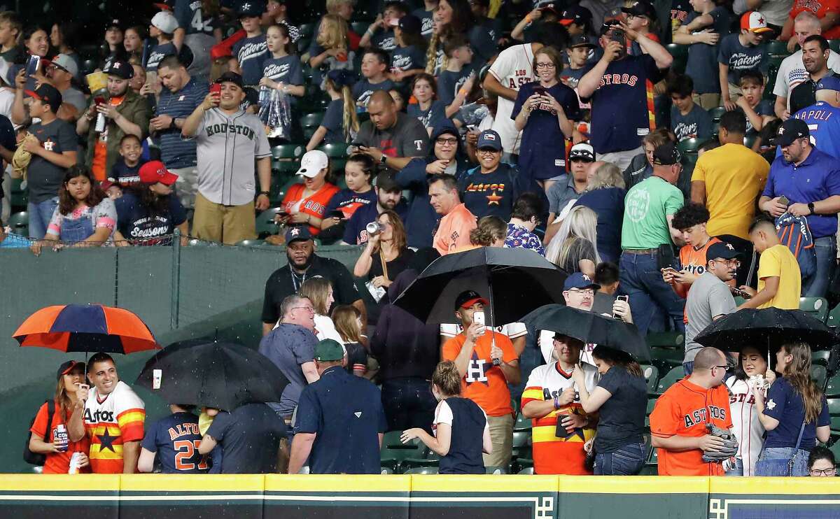 Houston Astros fans take cover under umbrellas as the heavy rain leaks into Minute Maid Park during the eighth inning in a major league baseball game between the Astros and Texas Rangers on Thursday, May 9, 2019, in Houston.
