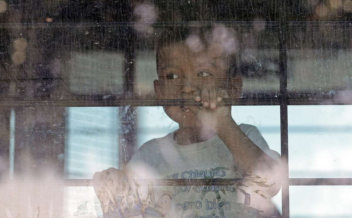 File - In this June 23, 2018, file photo, an immigrant child looks out from a U.S. Border Patrol bus leaving as protesters block the street outside the U.S. Border Patrol Central Processing Center in McAllen, Texas. Immigrant children described hunger, cold and fear in a voluminous court filing about the facilities where they were held in the days after crossing the border. Advocates fanned out across the southwest to interview more than 200 immigrant parents and children about conditions in U.S. holding facilities, detention centers and a youth shelter. The accounts form part of a case over whether the government is complying with a longstanding settlement over the treatment of immigrant youth in custody. (AP Photo/David J. Phillip, File)