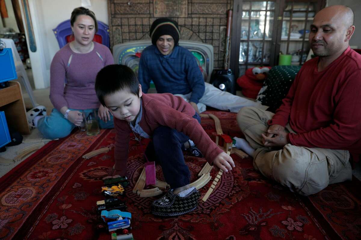 Hay Hov and his wife Catherine Depooter play with their son Robbie, who has autism, with Robbie's behaviorial therapist, Daniel Miranda, center,in their family's home in Oakland, Calif., on Monday, March 11, 2019. Hov is at risk of deportation because of a crime committed 19 years ago when he was a 19, and he now faces deportation to a country he doesn't recognize after being brought here at the age of 6 by his parents. His son has autism and needs both parents for proper care.