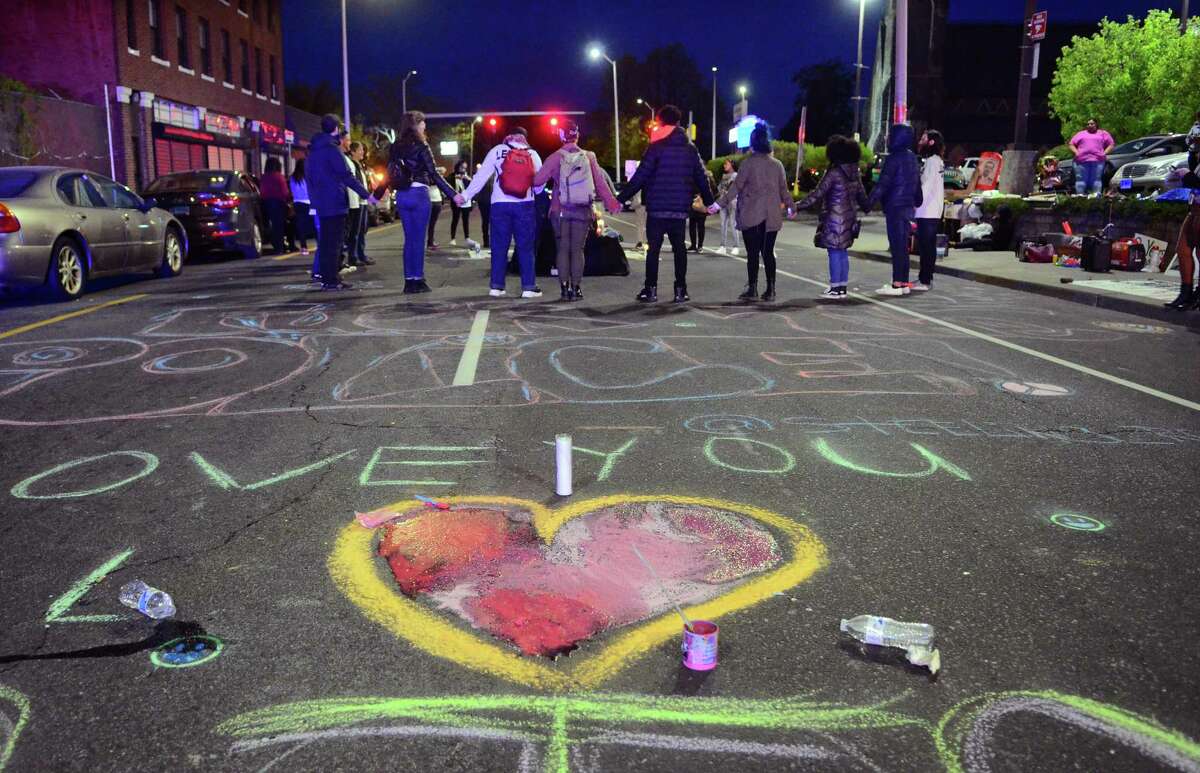 Activists and friends of Jayson Negron hold hands as they hold a vigil for him near the Walgreens along Fairfield Avenue in Bridgeport on Thursday to mark the second anniversary of Negron's death after he was fatally shot by a police officer near the pharmacy.