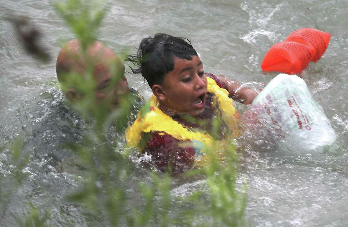 A Border Patrol Agent rescues a seven year old boy from Honduras after he fell out of a make shift raft and lost hold of his mother as Border Patrol agents respond to three rafts crossing the Rio Grande River in Eagle Pass, on Friday, May 10, 2019.