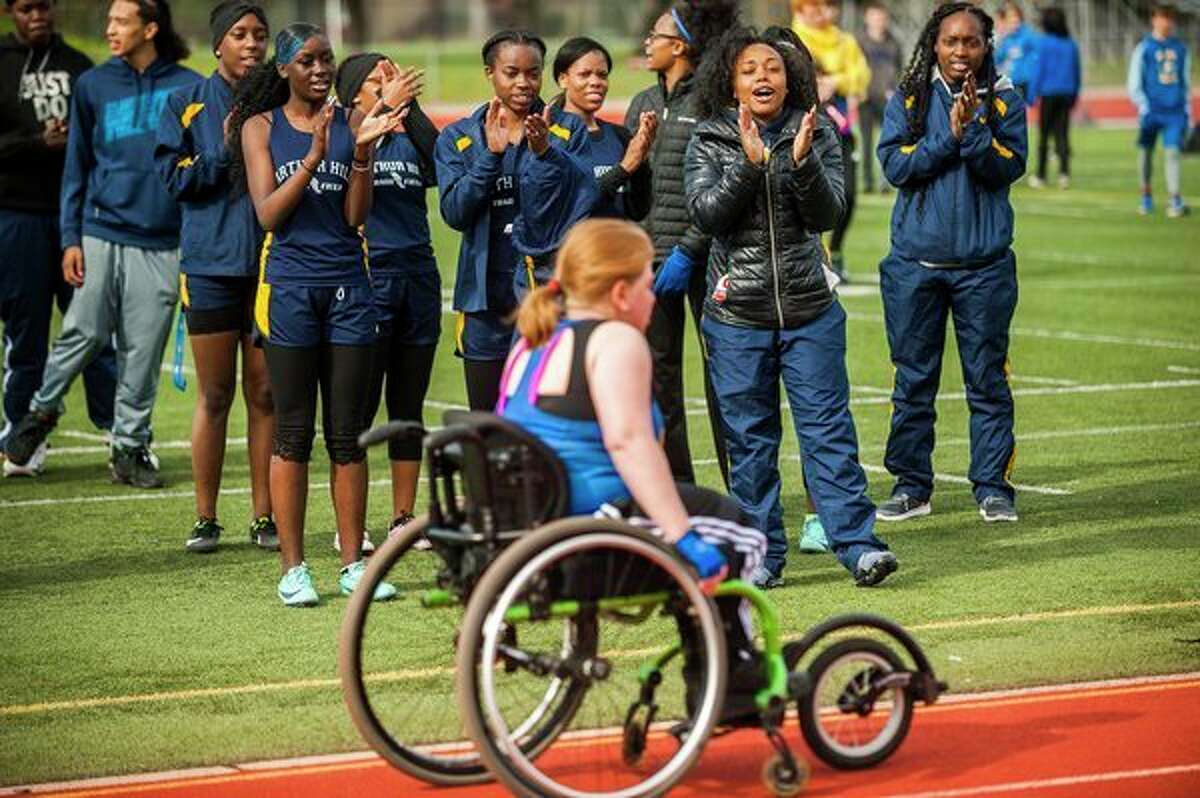 Athletes from Arthur Hill High School cheer on Midland High sophomore FaithAnne Sawicki as she competes in the 100-meter dash in her wheelchair during a track meet on Tuesday at Midland Community Stadium. (Katy Kildee/kkildee@mdn.net)