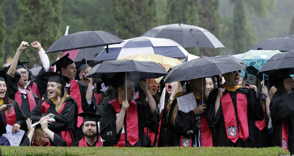Graduates cheer from under umbrellas during commencement ceremonies on the quad at Rice University Saturday, May. 11, 2019 in Houston, TX.
