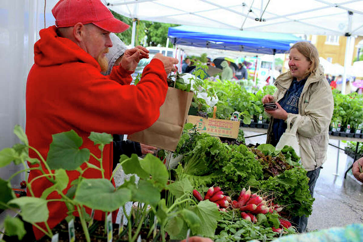A little rain didn’t stop Keith Biver, of Biver Farms, at left, from serving up his locally and organically grown produce and plants in downtown Edwardsville Saturday morning during opening weekend of Goshen Market’s 23rd season. Chilly, rainy May weather set the scene but excited patrons still supported the market’s return.