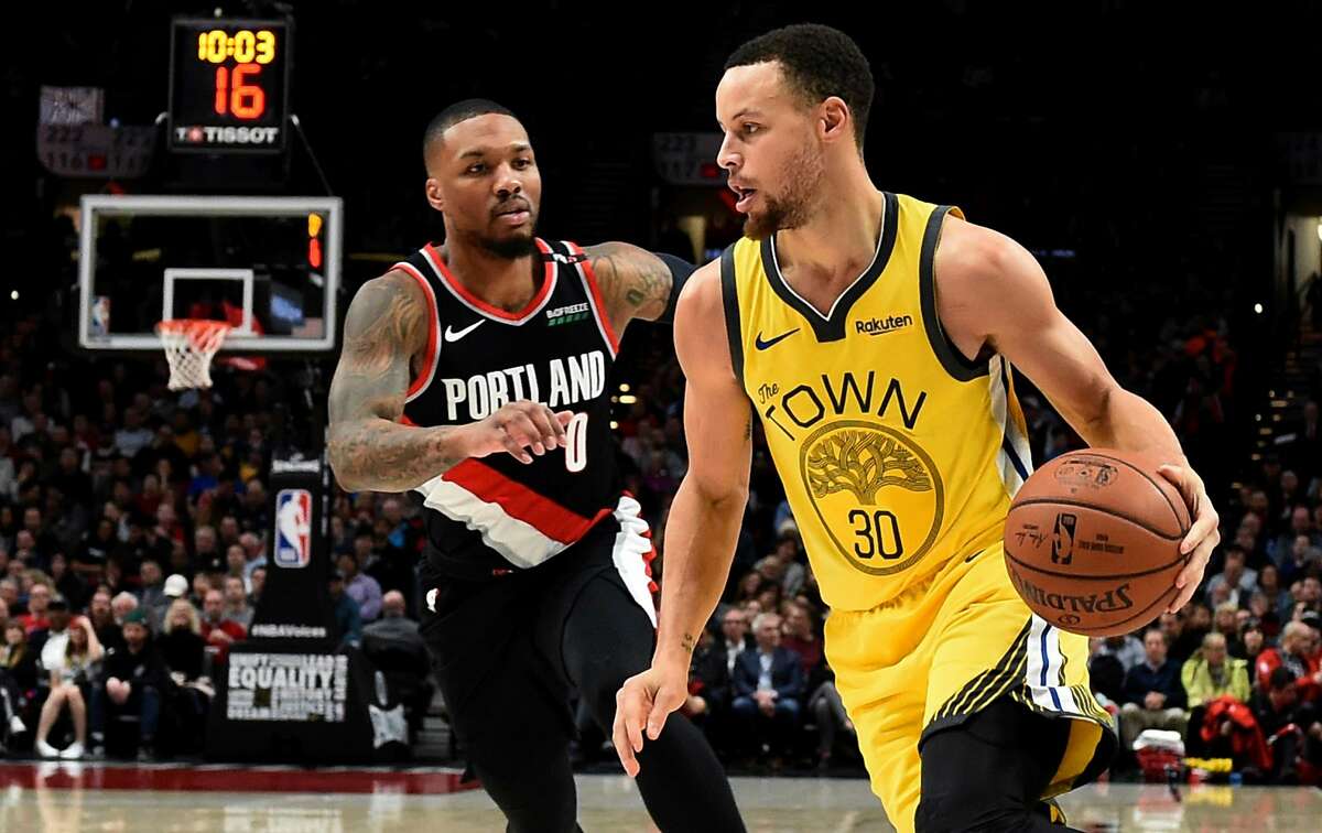 Golden State Warriors guard Stephen Curry, right, drives to the basket past Portland Trail Blazers guard Damian Lillard during the first half of an NBA basketball game in Portland, Ore., Wednesday, Feb. 13, 2019. (AP Photo/Steve Dykes)