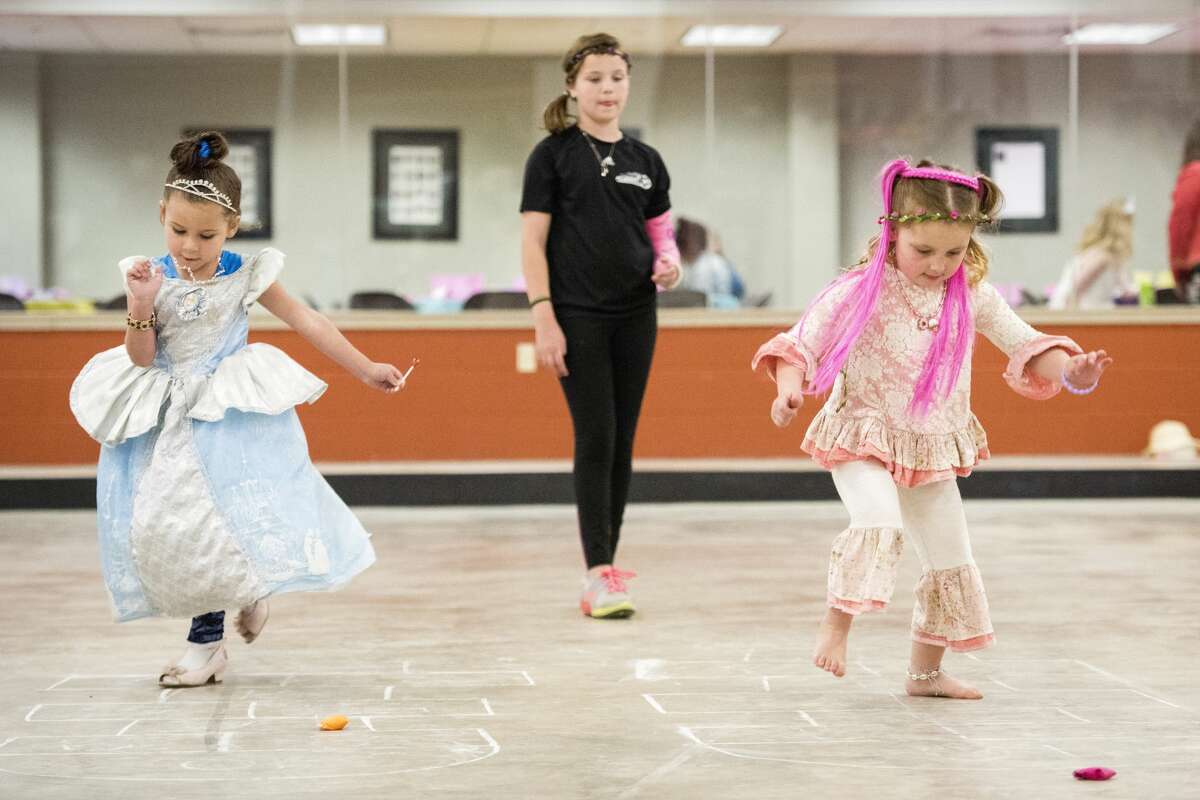 Zayleigh DeShone, 4, and and Blakely Dulude, 4, play hopscotch during a Mothers and Daughters Tea Party at the Midland Curling Club on Saturday. (Danielle McGrew Tenbusch/for the Daily News)