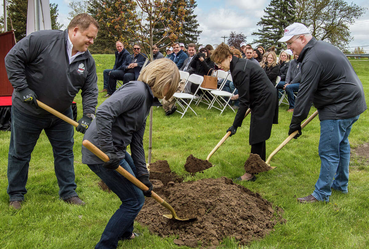 DuPont Global Business President and leader of "DuPont North" Tim Lacey, left, Midland Mayor Maureen Donker, center right, and DuPont CEO-elect Marc Doyle, right, plant a red maple sapling during a symbolic ceremony commemorating DuPont's presence in Michigan on Monday near US-10 and North Jefferson Avenue in Midland. (Ashley Schafer/ashley.schafer@hearstnp.com)