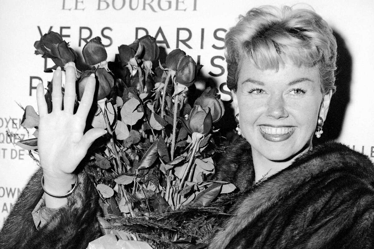FILE - In this April 15, 1955, file photo, American actress and singer Doris Day holds a bouquet of roses at Le Bourget Airport in Paris after flying in from London. The Doris Day Animal Foundation confirmed Day died early Monday, May 13, 2019, at her home in Carmel Valley, Calif. She was 97. (AP Photo, File)
