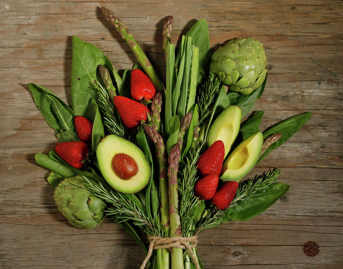 A bouquet of spring vegetables includes rosemary, asparagus, artichokes, strawberries and dandelion greens.
