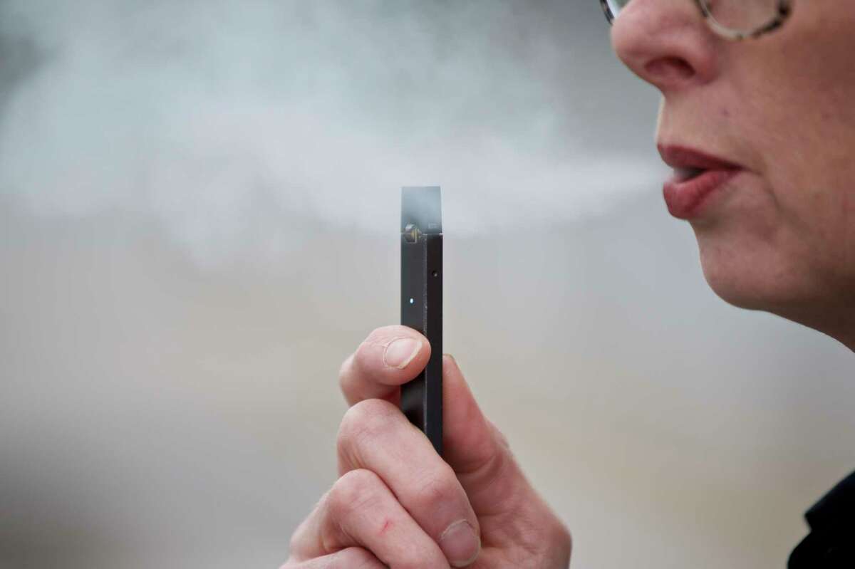 FILE - In this April 16, 2019, file photo, a woman exhales a puff of vapor from a Juul pen in Vancouver, Wash. (AP Photo/Craig Mitchelldyer, File)