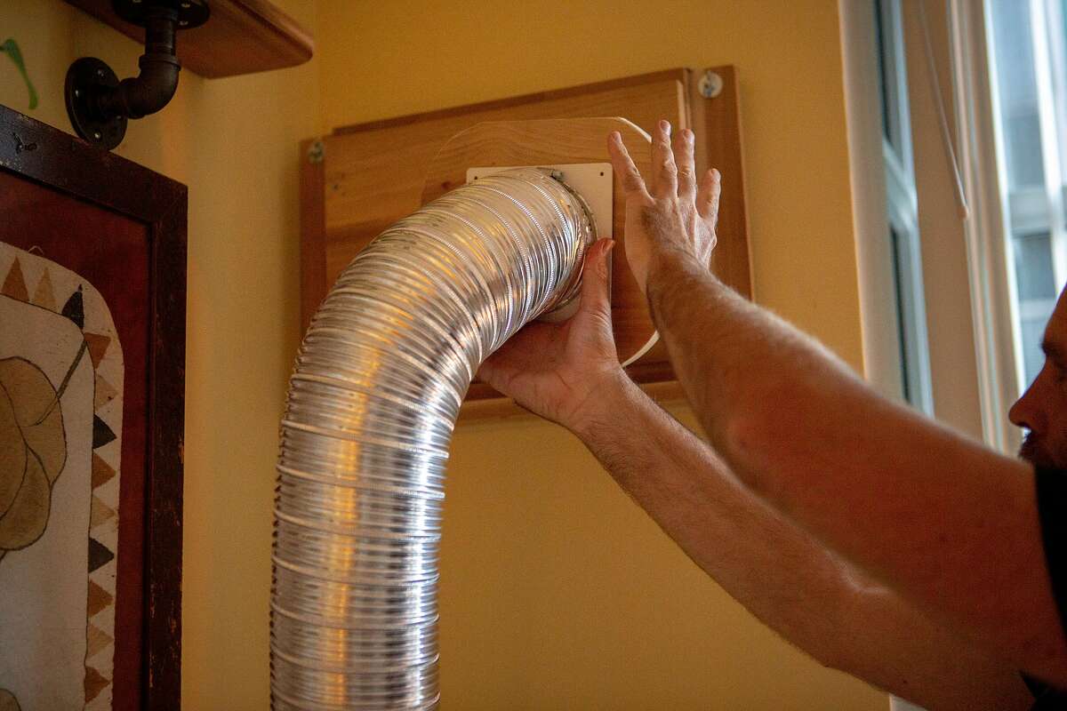 Mark Samples plugs in his wall ventilator that connects the air outside to an air cleaner in his bedroom on Friday, May 10, 2019, in San Francisco, Calif. The home has up to four air cleaners turned on at once as well as three carbon activated filters mounted on the walls to reduce the carbon allegedly coming in from Espetus, the restaurant across the street.