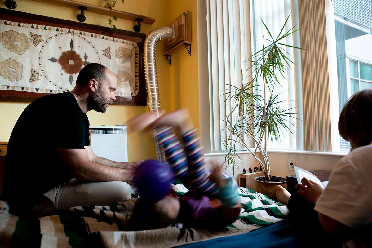 From left: Mark Samples checks on his daughter Sylvie, 3, and son William, 7, on Friday, May 10, 2019, in San Francisco, Calif. An air filter is seen behind them. The home has up to four air cleaners turned on at once as well as three carbon activated filters mounted on the walls to reduce the carbon allegedly coming in from Espetus, the restaurant across the street.