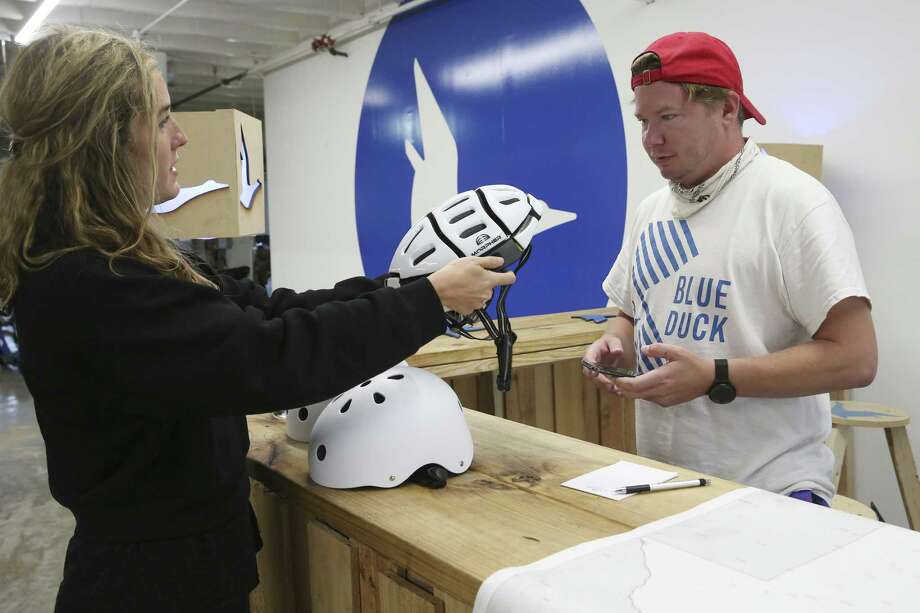 Blue Duck Vice President and Chief Marketing Officer Elizabeth Houston shows CEO Eric Bell a collapsible helmet at their warehouse and office space near the Pearl. Bell would like to position Blue Duck as the stylish but safety-conscious Volvo of scooter companies. Photo: Jerry Lara / © 2019 San Antonio Express-News