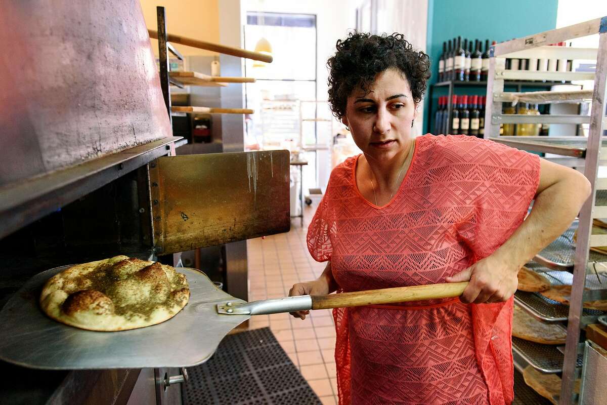 Owner Reem Assil pulls a Za'atar Man'oushe from the oven at Reem's in Oakland, Calif, on Wednesday, April 17, 2019.