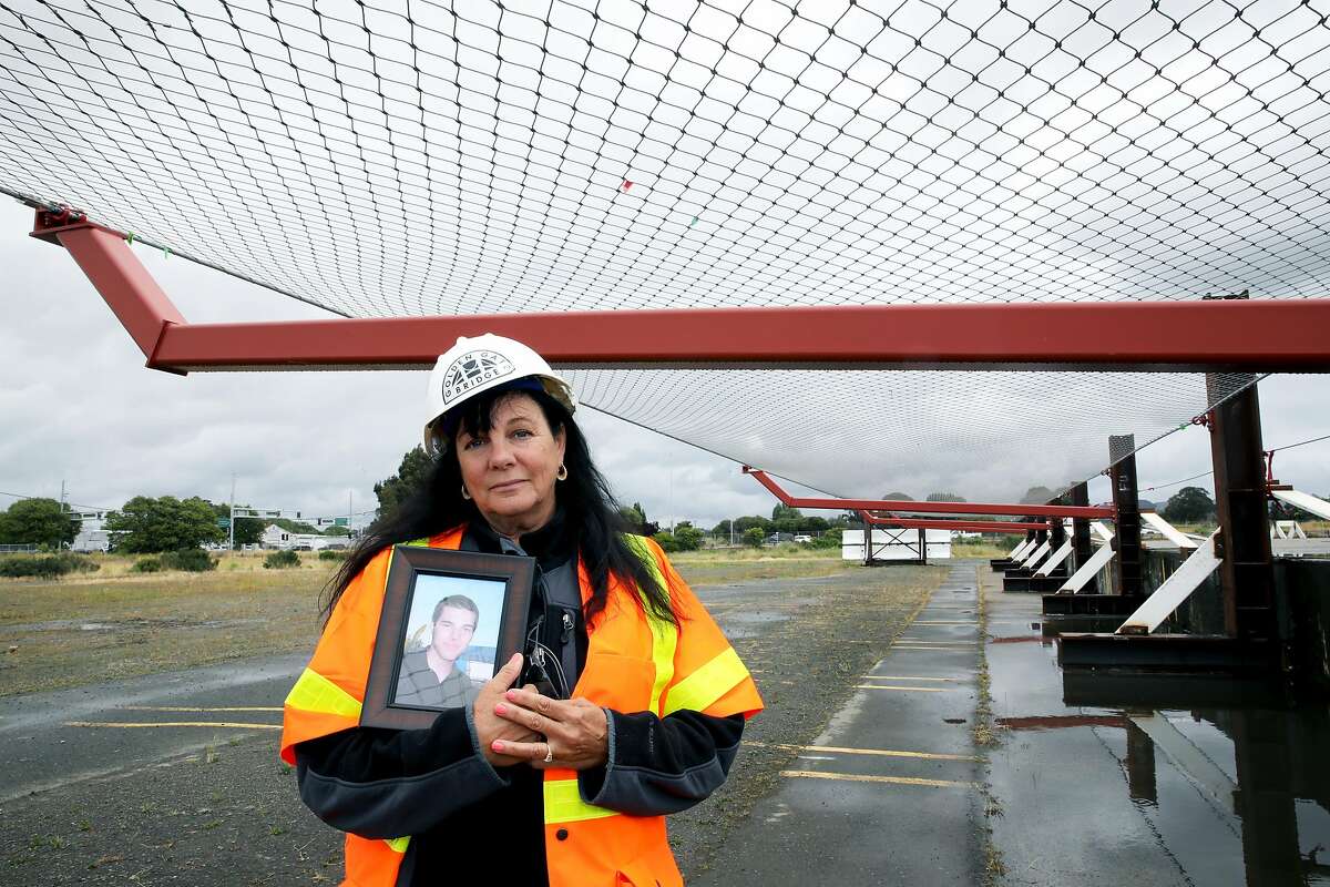 Dayna Whitmer holds a portrait of her son, Mattie, who at the age of 20 jumped from the Golden Gate Bridge on November 15, 2017, as she poses for a photograph at the Richmond Yard in Richmond, Calif., on Thursday, May 16, 2019. His body was never recovered. Whitmer, of Hercules, is standing underneath a suicide deterrent system net that will prevent anyone from easily jumping into the water below. "People were so upset; they thought it would ruin the look of the bridge and say it's going to make it ugly and it's not," Whitmer said. "It doesn't matter because it is a bridge and the net's only going to help."