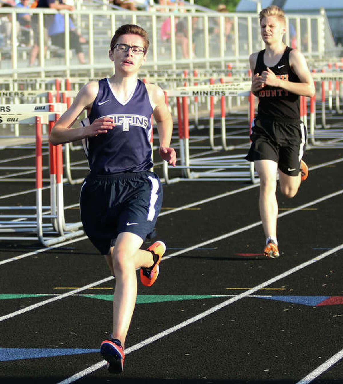 Father McGivney’s Brandon Ahring (left) approaches the finish line after overtaking Waverly’s Jake Gutzman in the final 100 meters to win the 3,200 Thursday at the Gillespie Class 1A Sectional. Ahring won in 10:37.18.