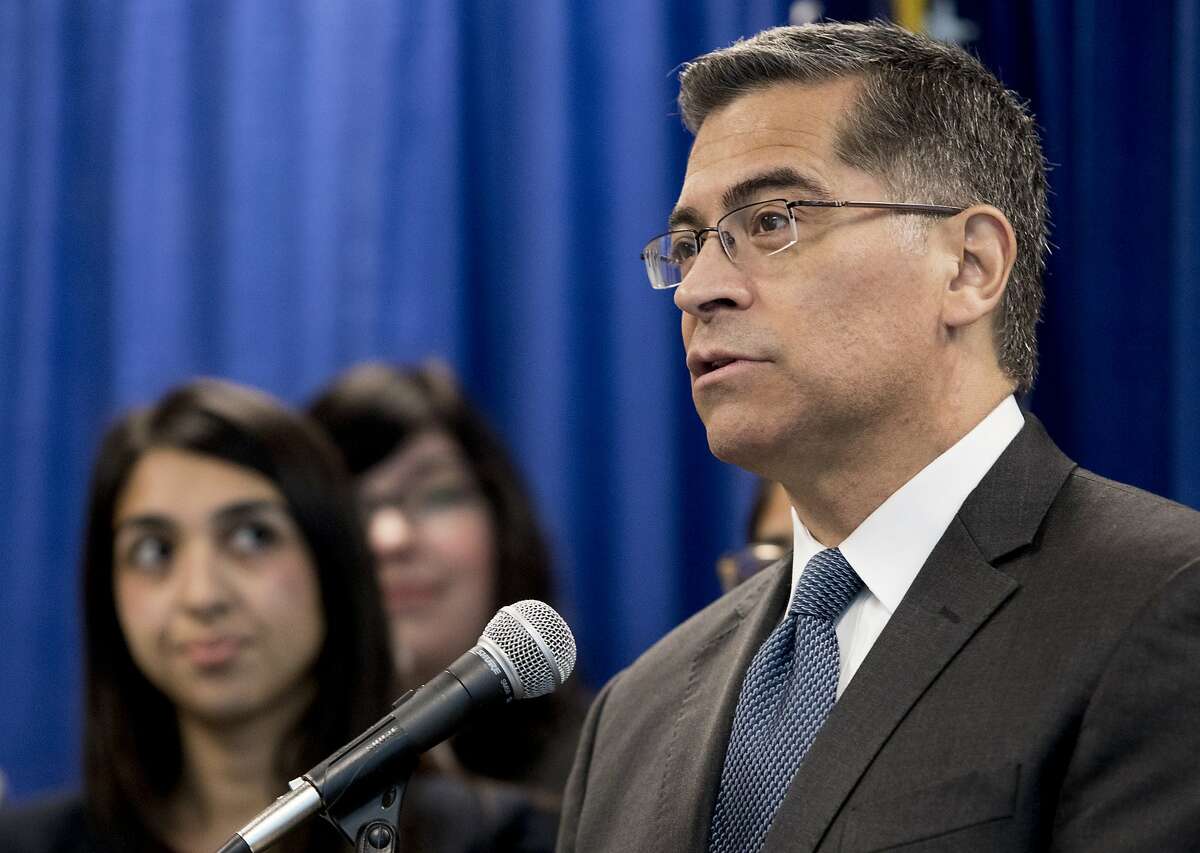 California Attorney General Xavier Becerra stands with members of his legal team as he unveils findings of a report on the state's immigration detention centers during a press conference held at the California Department of Justice office in San Francisco, Calif. Monday, Feb. 18, 2019.