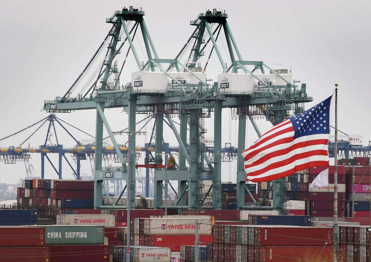 Chinese shipping containers are stored beside a U.S. flag after they were unloaded at the Port of Los Angeles in Long Beach, California on Tuesday. Global markets remain on red alert over a trade war between the two superpowers China and the US, that most observers warn could shatter global economic growth, and hurt demand for commodities like oil.