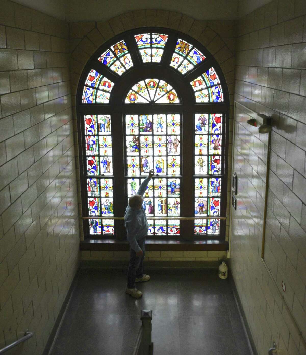 David Lawson, chairman of the Board of Education, points out section of a stained glass window, by Len R. Howard, in the old high school building, now known as the Lillis Administration building. The project was commissioned by the WPA's Federal Arts Program in 1936. New Milford is using a grant to have a consultant study the best way to use the East Street building.