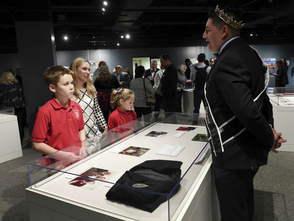 Isaac Castro, right, who represents Texas A&M University-San Antonio at cultural and civic events, speaks with Amy Porter, middle, who is a history professor, and her children, Dominick and Anna, during the grand opening of a special exhibit marking the 10th anniversary of the university in the Bexar County Archives Building on Wednesday, Feb. 20, 2019.