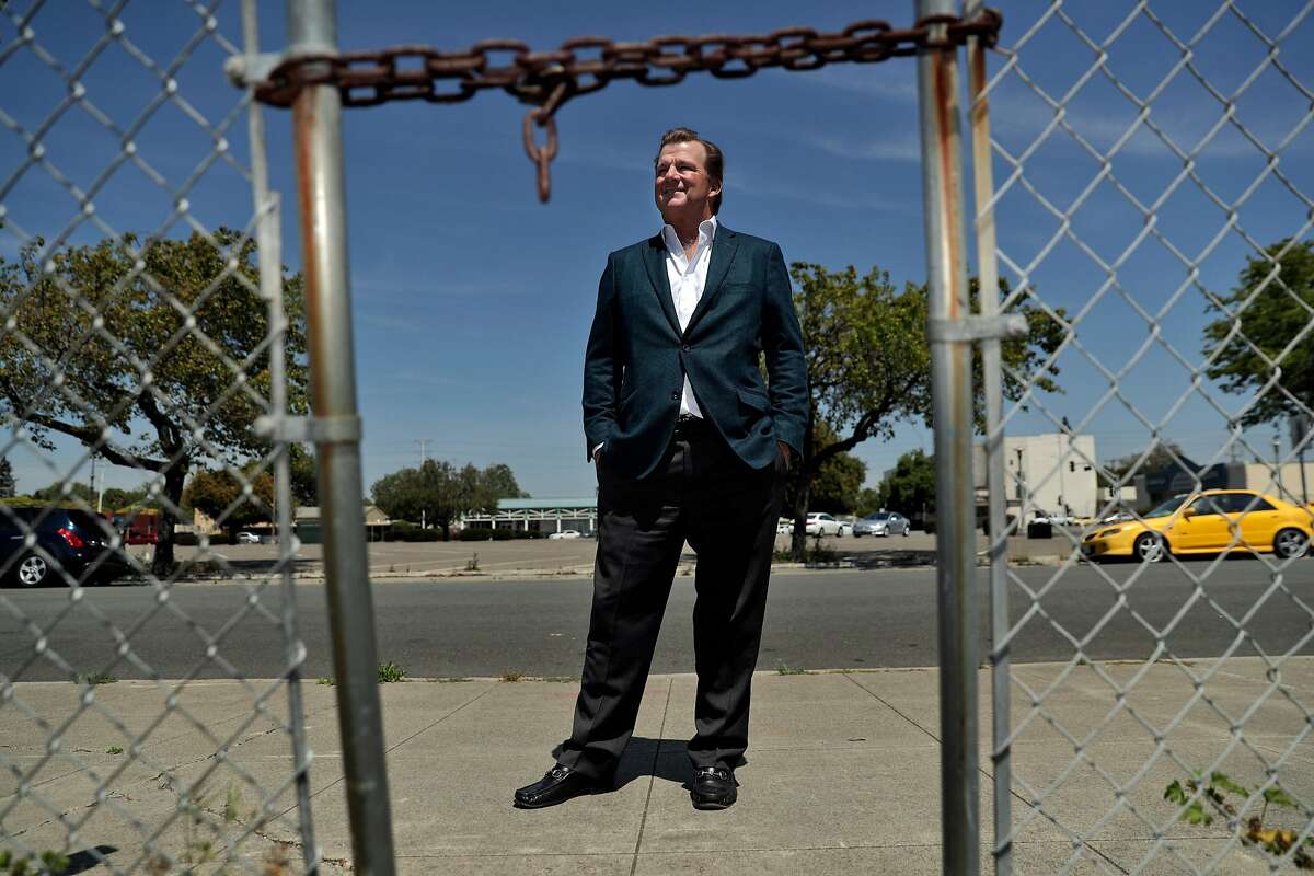 Developer Terry Demmon is seen through the chained gate at the former site of the first Mervyn's department store where he hopes to build a 163-unit combined housing and retail center in San Lorenzo, Calif., on Tuesday, May 7, 2019. Demmons claims the project is being delayed by unions which he claims are trying to force him to use union labor.