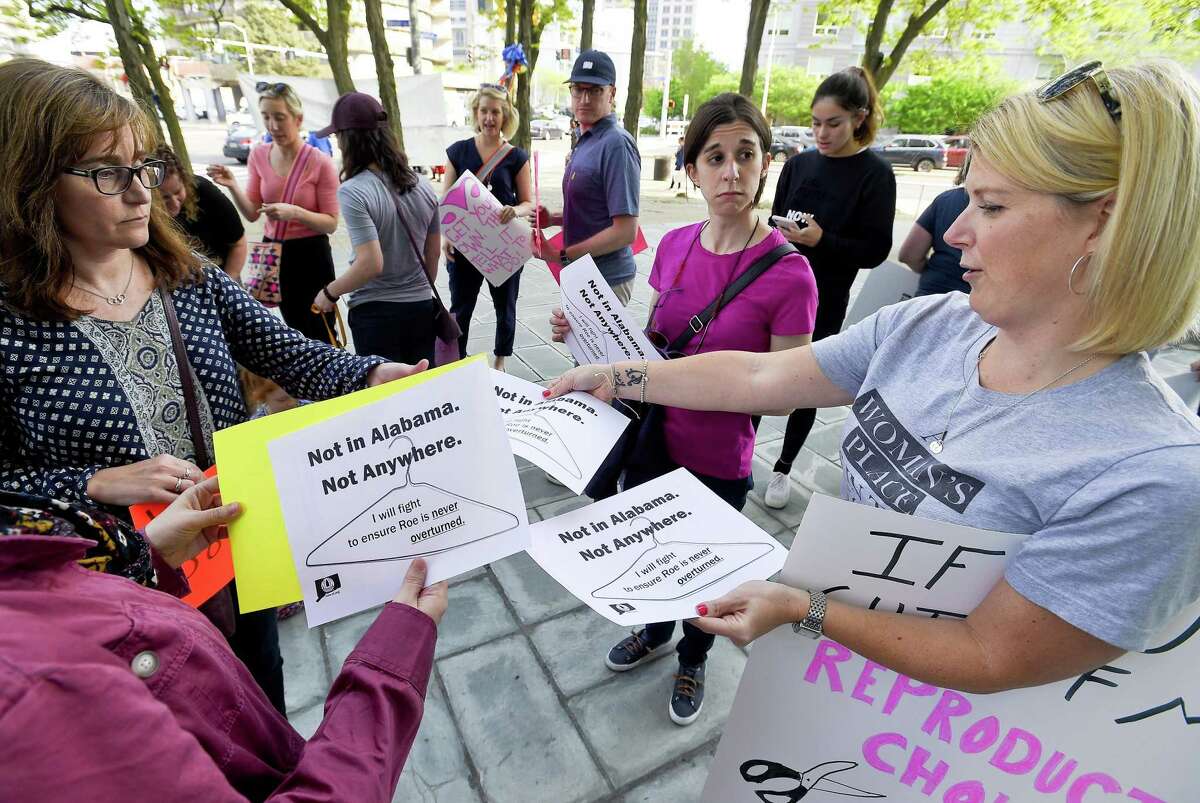 At right, Kristin O'Neil of Stamford passes out fliers as participants with the We Won't Go Back movement hold a rally outside the Stamford Government Center on May 17, 2019 in Stamford, Connecticut. Over 100 participants stood in solidarity protesting the recent Anti-Abortion decisions and changes in law in other states.