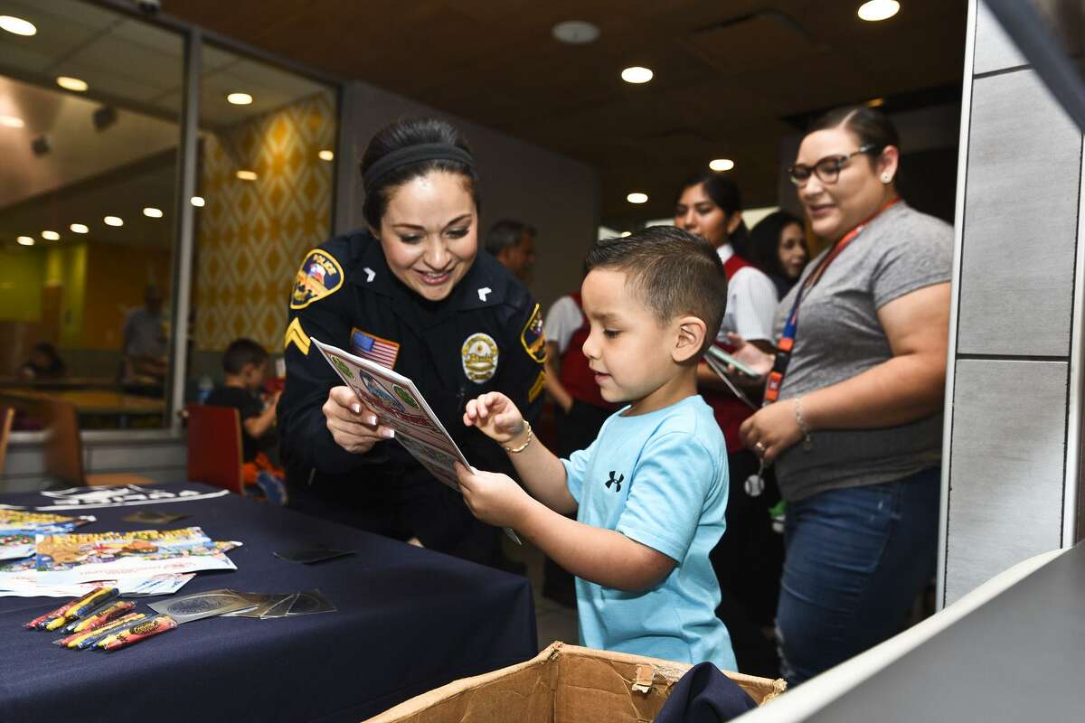 Laredo Police Department Investigator Gina Gonzales shows a book to young Lyam Tello on Saturday.