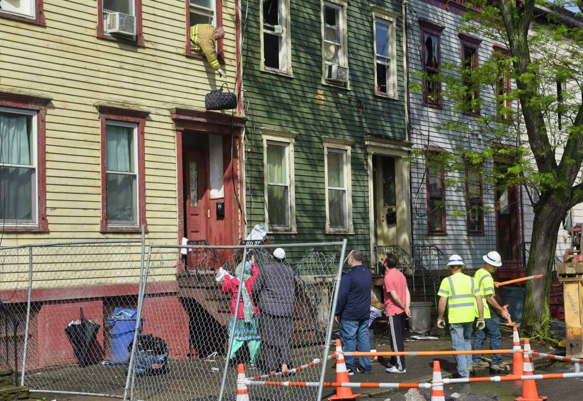 Dan Sherman, with the City of Albany Code Enforcement Department, drops a bag of clothes out of a window of one of the Bradford Street apartments damaged by fire on Monday, May 20, 2019, in Albany, N.Y. Sherman was retrieving some items for a family. An early morning fire on Sunday damaged several apartment buildings on Bradford Street. (Paul Buckowski/Times Union)