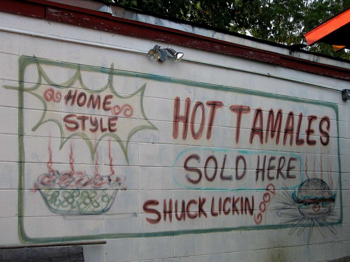 Delta tamales. A sign on the side of Delta Fast Foods on U.S. 61 in Cleveland, Miss., promises tamales that are "shuck lickin' good." Photo by Rod Davis, staff. July 2004.
