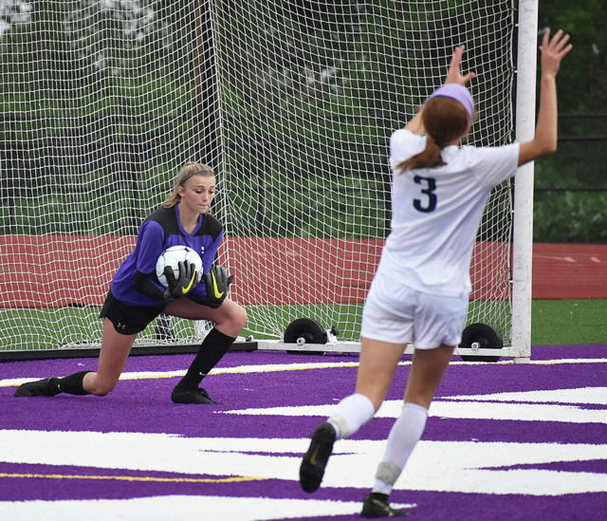 Edwardsville’s Emma Hensley scoops up a shot as O’Fallon’s Aubrey Mister reacts to the play in the first half.