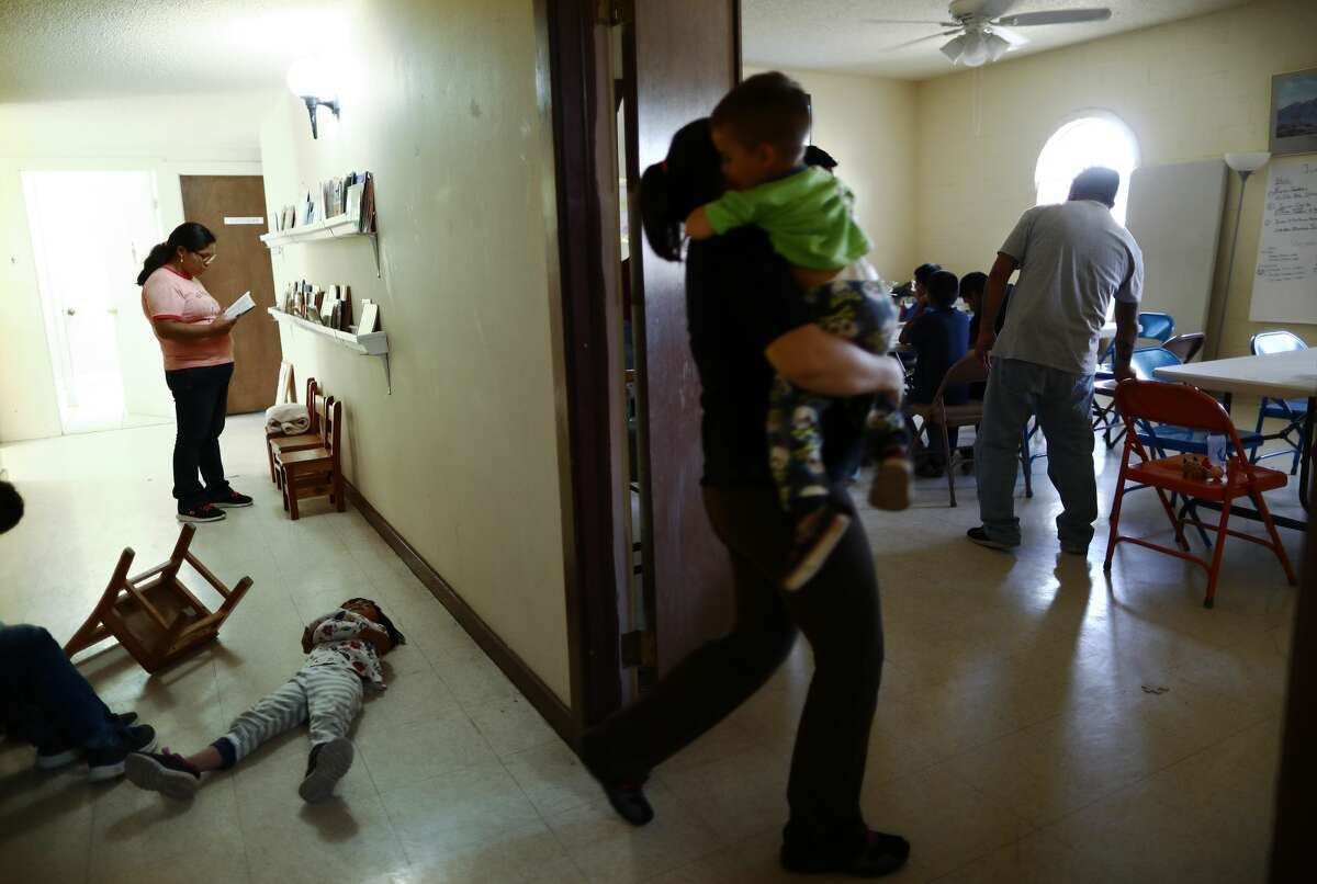 Migrants gather as a child plays on the floor in a church shelter for migrants who seek asylum on May 16 in Las Cruces, N.M.. After being released by the U.S. Immigration and Customs Enforcement to the shelter, asylum-seekers are then normally transferred from the shelter to their U.S. sponsors as they await their asylum requests. Approximately 1,000 migrants per day are being released by authorities in the El Paso sector of the U.S.-Mexico border, which includes Las Cruces. Las Cruces has processed over 5,000 asylum seekers since it began receiving them from the Border Patrol on April 12.