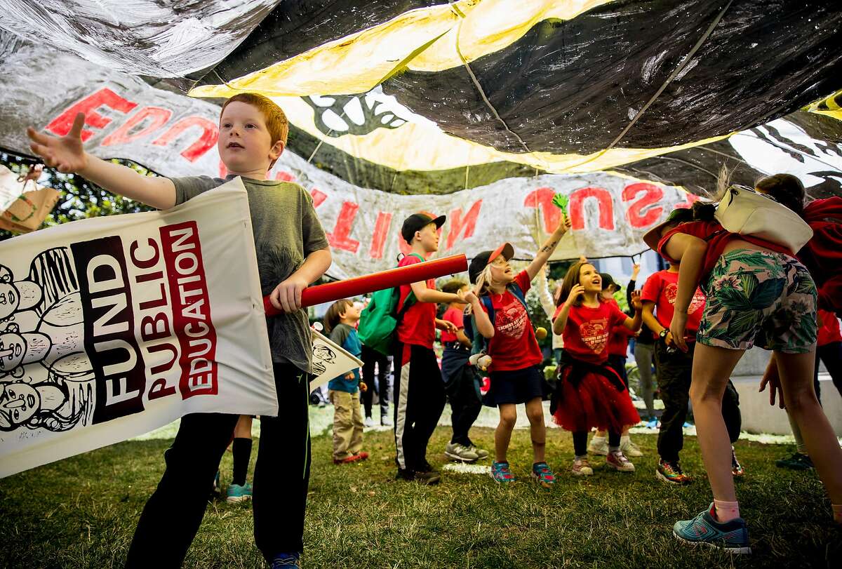 Students from Melrose Leadership Academy in Oakland play underneath a large banner during a march and rally held at the California State Capitol by public school teachers, administrators and supports urging state legislators to provide more funding for public schools in Sacramento, Calif. Wednesday, May 22, 2019.
