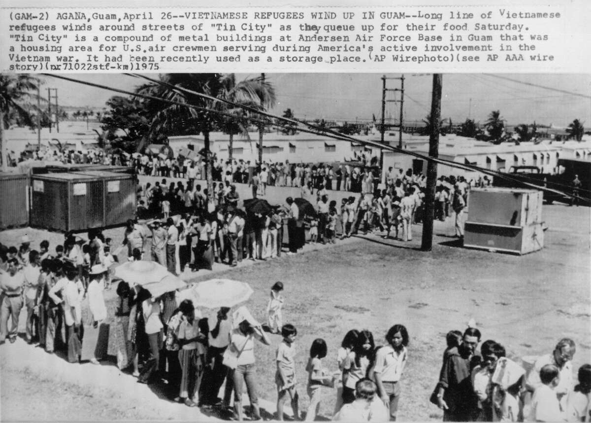 (GAM-2) AGANA, Guam, April 26--VIETNAMESE REFUGEES WIND UP IN GUAM--Long line of Vietnamese refugees winds around streets of 'Tin City' as they queue up for their food Saturday. 'Tin City' is a compound of metal buildings at Andersen Air Force Base in Guam that was a housing area for U. S. air crewmen serving during America's active involvement in the Vietnam war. It had been recently used as a storage place. (AP Wirephoto) 1975
