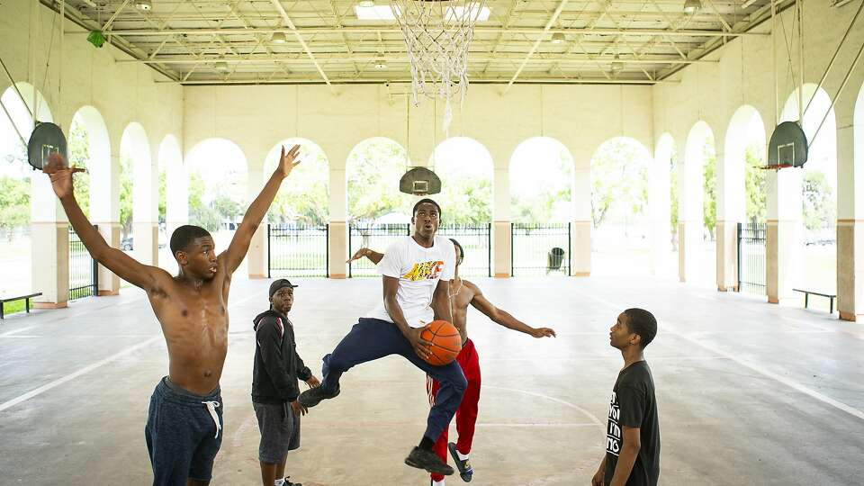 Brodrick Lewis, 17, center, shoots while playing basketball with friends at MacGregor Park, Wednesday, May 22, 2019. The teenagers had the day off from Northside High School, and they came to the park to play basketball on the shaded court.