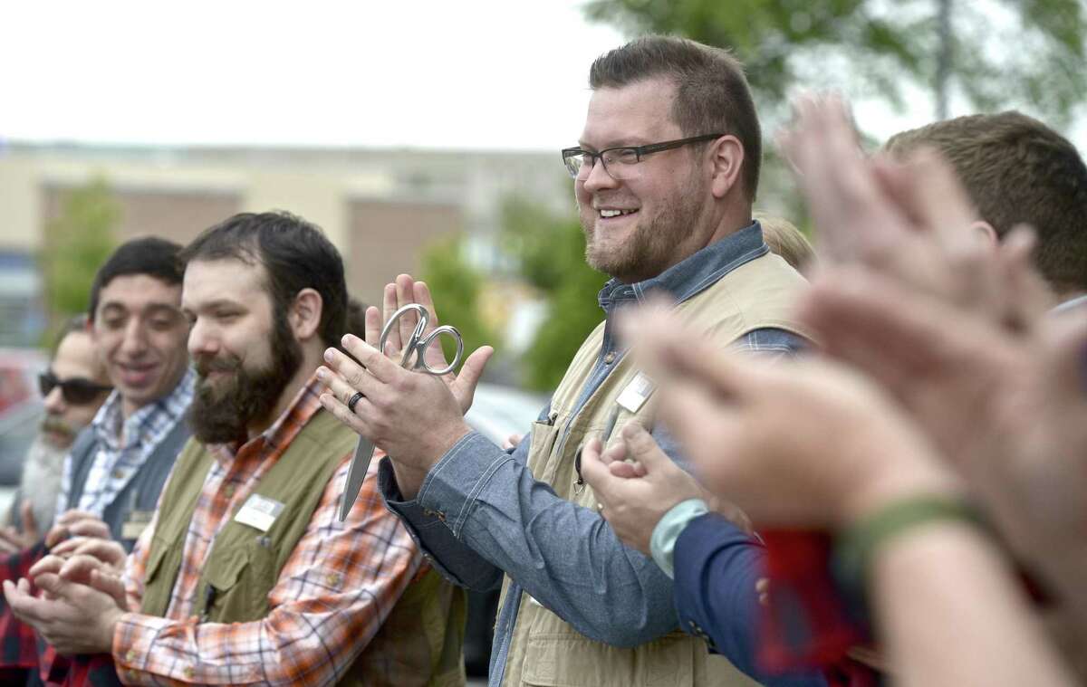 Sam Reynolds, store manager of the new Duluth Trading Co store in the Shops at Marcus Dairy shopping center, joins employees in a ribbon cutting ceramony for the new store on Thursday, May 23, 2019, in Danbury, Conn,