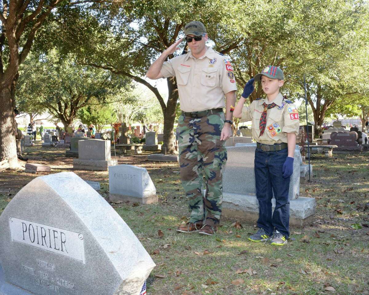Jack Armenta, 10, of Boy Scout Pack 548 and his father Ben Armenta salute after laying a wreath at the grave of a military veteran on National Wreaths Across America Day at Magnolia Cemetery, Saturday, December 15, 2018 in Katy, TX.